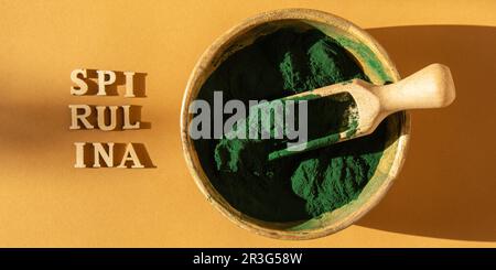 Blau-grüne Algen-Spirulina-Pulver in Bambus-Eco-Schüssel mit dem Text SPIRULINA. Superpulver im Löffel. Nahrungsergänzungsquelle von Prote Stockfoto