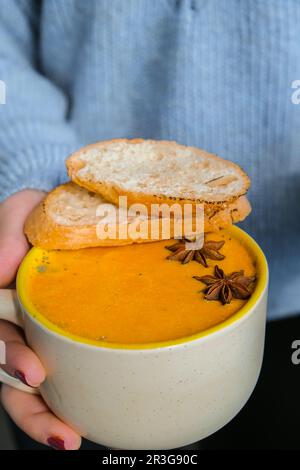 Eine Frau mit hausgemachter Karotte, Ingwerkurcuma, scharfer Suppe. Traditionelle Kürbissuppe der Saison mit cremiger, seidiger Konsistenz. Gesunde ve Stockfoto