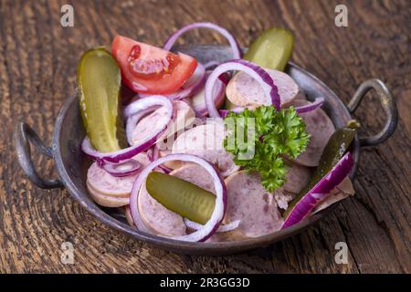Bayerischer Wurstsalat auf dunklem Holz Stockfoto