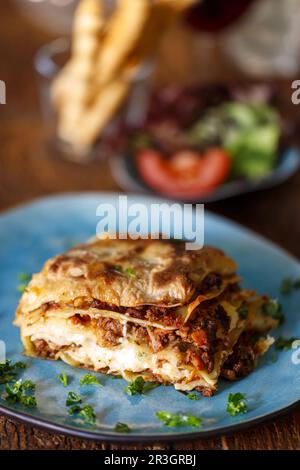 Frische Lasagne auf blauem Teller Stockfoto