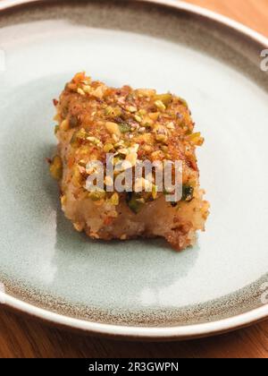 Syrischer Grießkuchen mit Zuckersirup, leckerer Harisse auf blauer Keramikplatte, syrisches Dessert Stockfoto