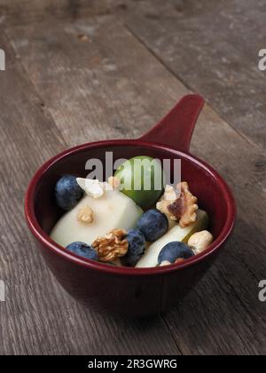 Bio-Lebensmittel in einer Schüssel, gesunde Lebensweise, Früchte und Nüsse, vegetarische Lebensmittel, Holztisch, Blick von oben Stockfoto