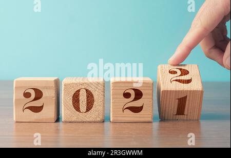 Drehen von Holzwürfeln mit der Jahreszahl 2021 und 2022, Neujahrskonzept, saisonale Weihnachtszeit Stockfoto