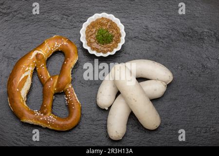 Bayerische Weißwürste auf schwarzem Schiefer Stockfoto