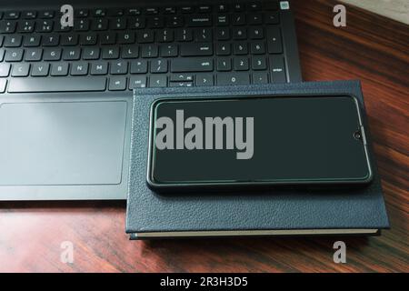 Flach liegender Schreibtisch mit Notebook, Mobiltelefon und Laptop auf Holzhintergrund. Stockfoto