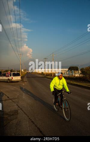Nealtikan, Mexiko. 23. Mai 2023. Ein Einheimischer ist auf dem Weg zur Arbeit, während der Vulkan Popocatepetl im Hintergrund Asche, Dampf und Gas ausstößt. Popocatépetl ist einer der aktivsten Vulkane in Mexiko. Es gibt seit Tagen Asche, Dampf und Gas aus. Die Experten gingen jedoch davon aus, dass die vulkanische Aktivität begrenzt sein wird, wie von der Behörde für Katastrophenschutz berichtet wurde. Kredit: Celacanto//dpa/Alamy Live News Stockfoto