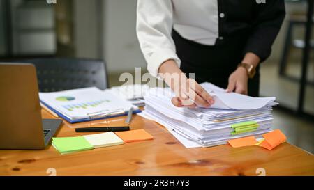 Nahaufnahme einer Geschäftsfrau, die Geschäftsdokumente an ihrem Schreibtisch überprüft und in ihrem Büro arbeitet. Stockfoto