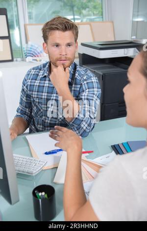 Die Designerin saß am Schreibtisch und diskutierte mit einer Kundin Stockfoto