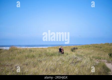 Wandern Älteres Paar auf dem Weg in hohem Gras entlang der Küste im Pazifischen Nordwesten, atmen gesunde frische Luft, um die Immunität zu stärken Stockfoto