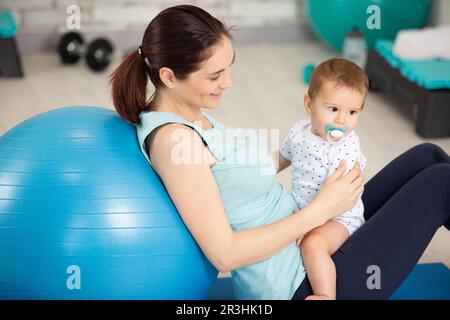 Mutter mit Kind, das mit Sportball Fitnessübungen macht Stockfoto