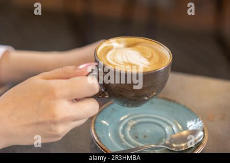 Die Frau hält eine Tasse Kaffee im Café Stockfoto