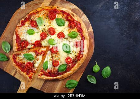 Traditionelle neapolitanische italienische Pizza margherita mit Tomaten und Mozzarella, serviert von oben auf einer hölzernen Pizzaschaufel mit Tee Stockfoto