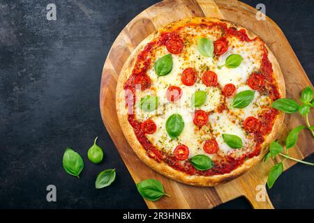 Traditionelle neapolitanische italienische Pizza margherita mit Tomaten und Mozzarella, serviert von oben auf einer hölzernen Pizzaschaufel mit Tee Stockfoto