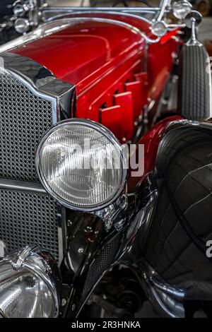 Fragment eines glänzenden roten und schwarzen Retro-Autos mit einzigartigem Design und elegantem Chromgitter in diesem Oldtimer und runden Scheinwerfern Stockfoto