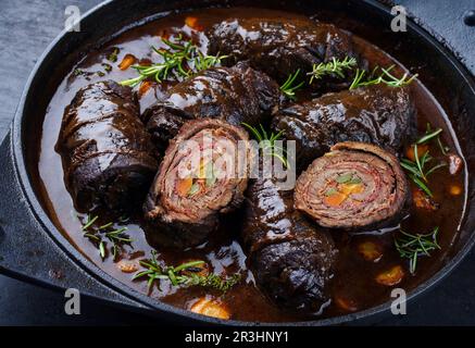 Traditionelle langsam gekochte deutsche Wagyu-Rinderrouladen mit Gemüse und Speck, serviert in scharfer Soße als Nahaufnahme in einem Design Stockfoto