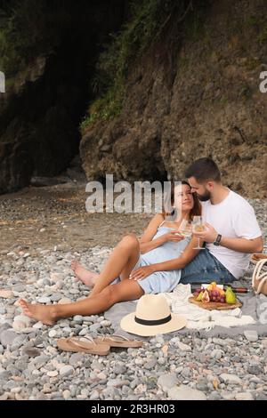 Glückliches junges Paar, das ein Picknick am Strand macht Stockfoto