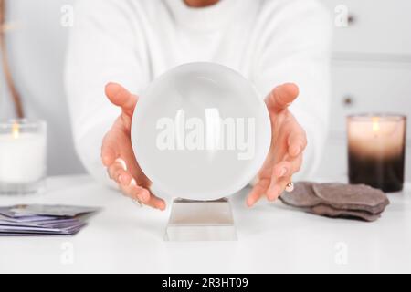 Wahrsager, die Kristallkugel benutzen, um die Zukunft am Tisch im Haus vorherzusagen, Nahaufnahme Stockfoto