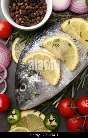 Frischer dorado-Fisch und Gewürze auf schwarzem Tisch, flach liegend Stockfoto