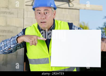 Arbeiter, der mit dem Finger auf ein leeres Brett zeigt Stockfoto