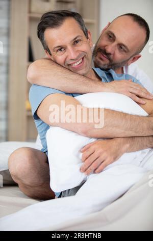 Glückliches homosexuelles Paar, das im Bett kuschelt Stockfoto