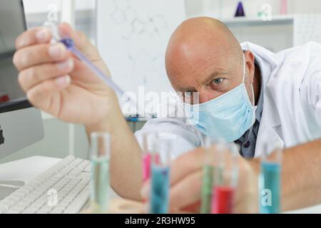 Humanwissenschaftler mit Autopipette und Kolben im medizinischen Labor Stockfoto