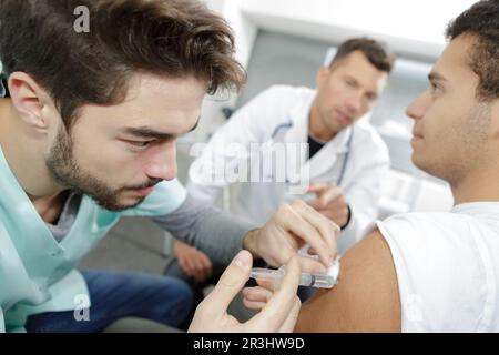 Junger Arzt, der den Patienten die Injektion gibt Stockfoto