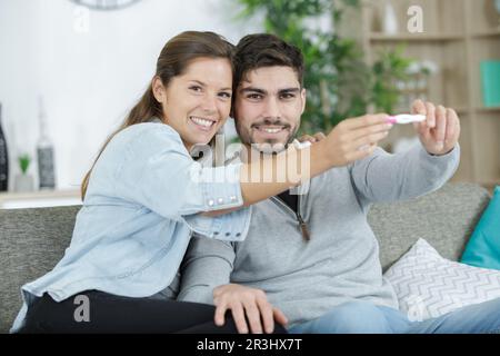 Glückliche junge Frau hat einen positiven Schwangerschaftstest Stockfoto