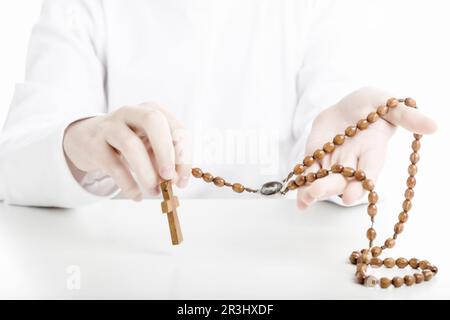 Ein lateinamerikanischer Junge hält Rosenkranz mit beiden Händen Stockfoto