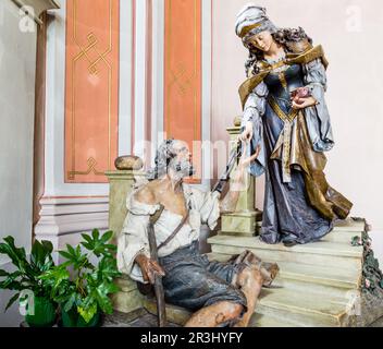 Hölzerne Statue von St. Elizabeth mit Bettler als wohltätige Geste Stockfoto