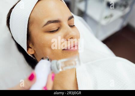 Kaukasische Frau bekommen Gesichtspeeling Verfahren in einer Schönheitsklinik, Nahaufnahme. Verjüngende Gesichtsgasbehandlung. Hydro Air Haut Reinigung Operat Stockfoto