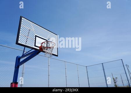 Fotos eines Basketballkörpers auf einem leeren Freiluftplatz am blauen Himmel. Stockfoto