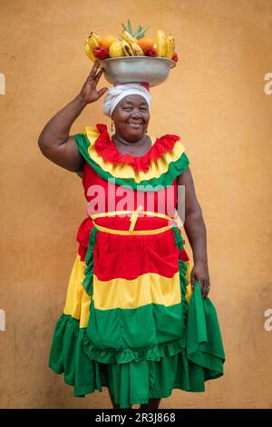 Fröhlicher Straßenverkäufer mit frischem Obst, auch bekannt als Palenquera, in der Altstadt von Cartagena, Kolumbien. Glückliche afrokolumbianische Frau in traditioneller Kleidung. Stockfoto