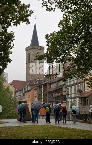 Gruppe von Menschen im Regen vor der Kraemer Brücke und der Aegidienkirche, Erfurt, Deutschland Stockfoto