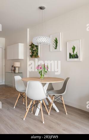 Modernes, stilvolles Wohnzimmer mit rundem Esstisch, Konsole und dekorativen Accessoires an den Wänden. Hotelkonzept in einem 5-Sterne-Hotel Stockfoto