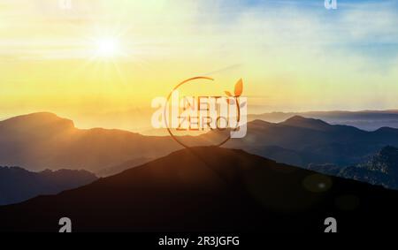 NET Zero-Schild auf dem Gipfel des Berges bei Sonnenuntergang, umgeben von umweltfreundlicher Natur. Netto-Null bedeutet einen enormen Rückgang beim Kohle-, Öl- und Gasverbrauch. Eco-Banner Stockfoto
