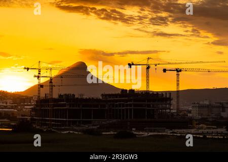 Baukräne auf der Baustelle bei Sonnenuntergang in Kapstadt Stockfoto