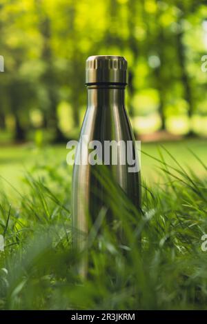 Wasserflasche. Wiederverwendbare Wärmflasche aus Stahl auf grünem Gras. Nachhaltiger Lebensstil. Ohne Plastik, ohne Abfall, ohne Leben. Geh Stockfoto