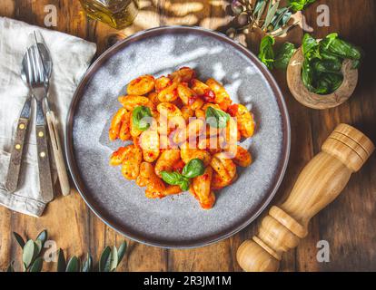 Italienischer Gnocchi mit Tomatensoße und Basilikum auf Holzhintergrund Stockfoto