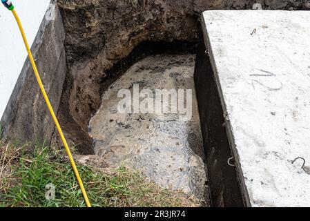 Klärbehälter aus Beton mit einem Fassungsvermögen von 10 Kubikmetern im Garten neben dem Haus, sichtbares Wasser darunter. Stockfoto