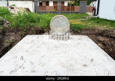 Klärbehälter aus Beton mit einem Fassungsvermögen von 10 Kubikmetern im Garten neben dem Haus, sichtbares Wasser darunter. Stockfoto