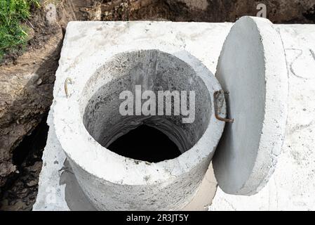 Klärbehälter aus Beton mit einem Fassungsvermögen von 10 Kubikmetern im Garten neben dem Haus, sichtbares Wasser darunter. Stockfoto