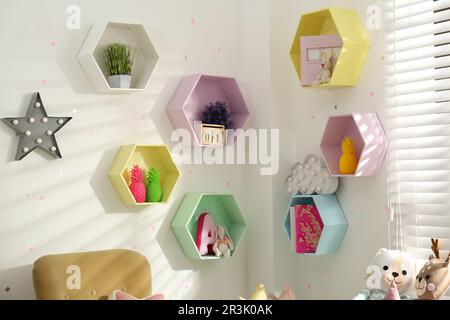 Sechseckige Regale an der weißen Wand im Kinderzimmer. Innendesign Stockfoto