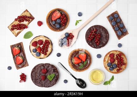 Frisches Roggen-Knusperbrot, knusprige Reiskuchen und Zwieback mit verschiedenen Belägen auf einem weißen Tisch, flach liegend Stockfoto