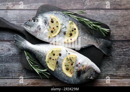 Frischer dorado-Fisch, Zitronenscheiben und Rosmarin-Zweige auf Holztisch, Draufsicht Stockfoto