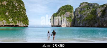 Ein paar Männer und Frauen in den Flitterwochen, die an einem tropischen Strand spazieren Stockfoto