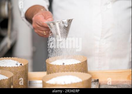 Konditorin serviert traditionelle italienische Panettones mit Puderzucker. Stockfoto