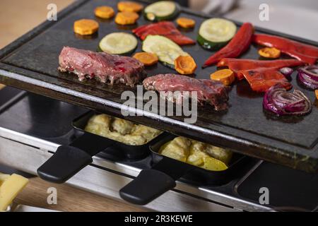 Schweizer Raclette mit Fleisch und Gemüse Stockfoto