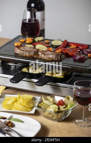 Schweizer Raclette mit Fleisch und Gemüse Stockfoto