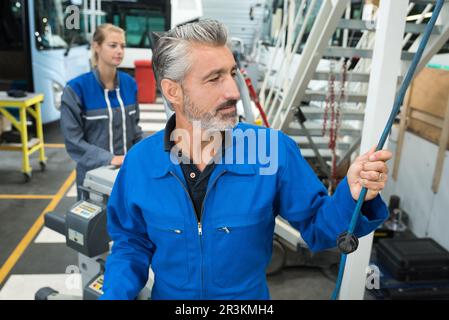 Mechaniker greift nach Luftschlauch in der Busgarage Stockfoto