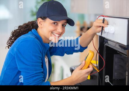 Weibliche Ingenieurin, die den Ofen mit einem Multimeter prüft Stockfoto